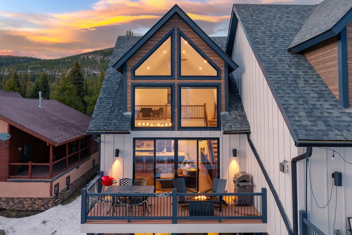 This exterior shot features a welcoming balcony seating area, a fire pit, and a mountain backdrop under a tranquil sunset. The scene suggests opportunities for outdoor dining, socializing, and basking in resort-level leisure.