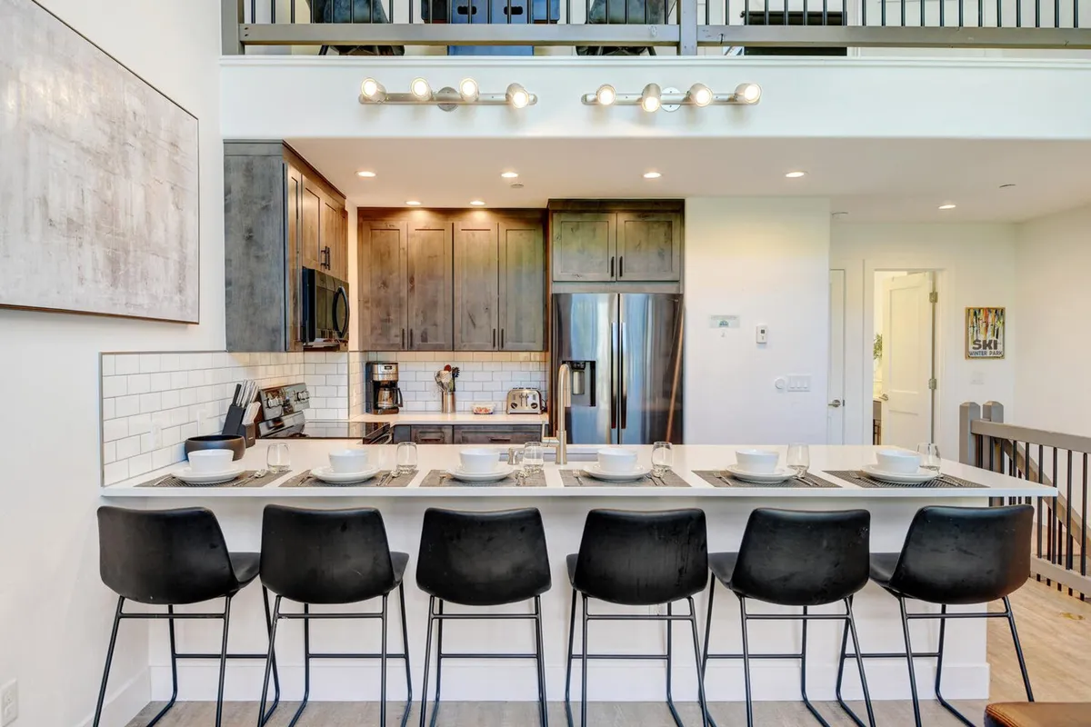 A bright, modern kitchen featuring a spacious island with bar stools, sleek stainless steel appliances, and contemporary cabinetry. The layout is open and inviting, perfect for cooking together or enjoying a casual breakfast.